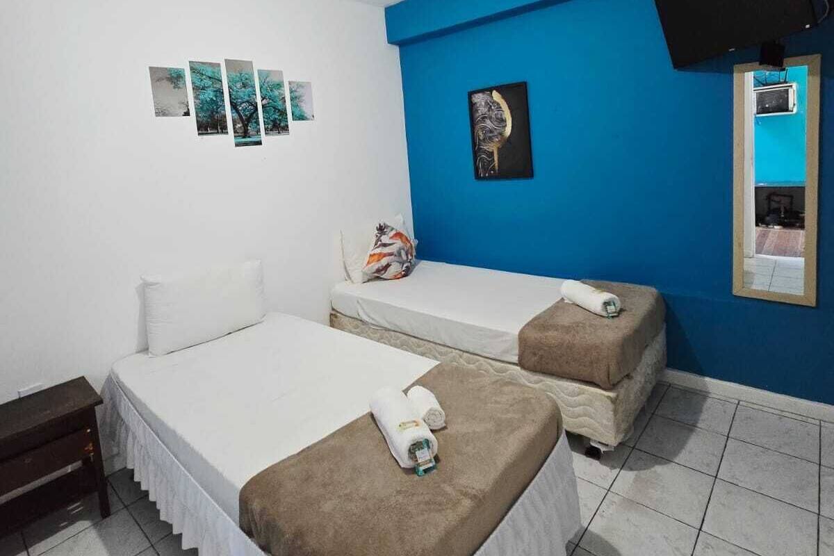 Une chambre avec deux lits, une télévision et des œuvres d’art accrochées aux murs.