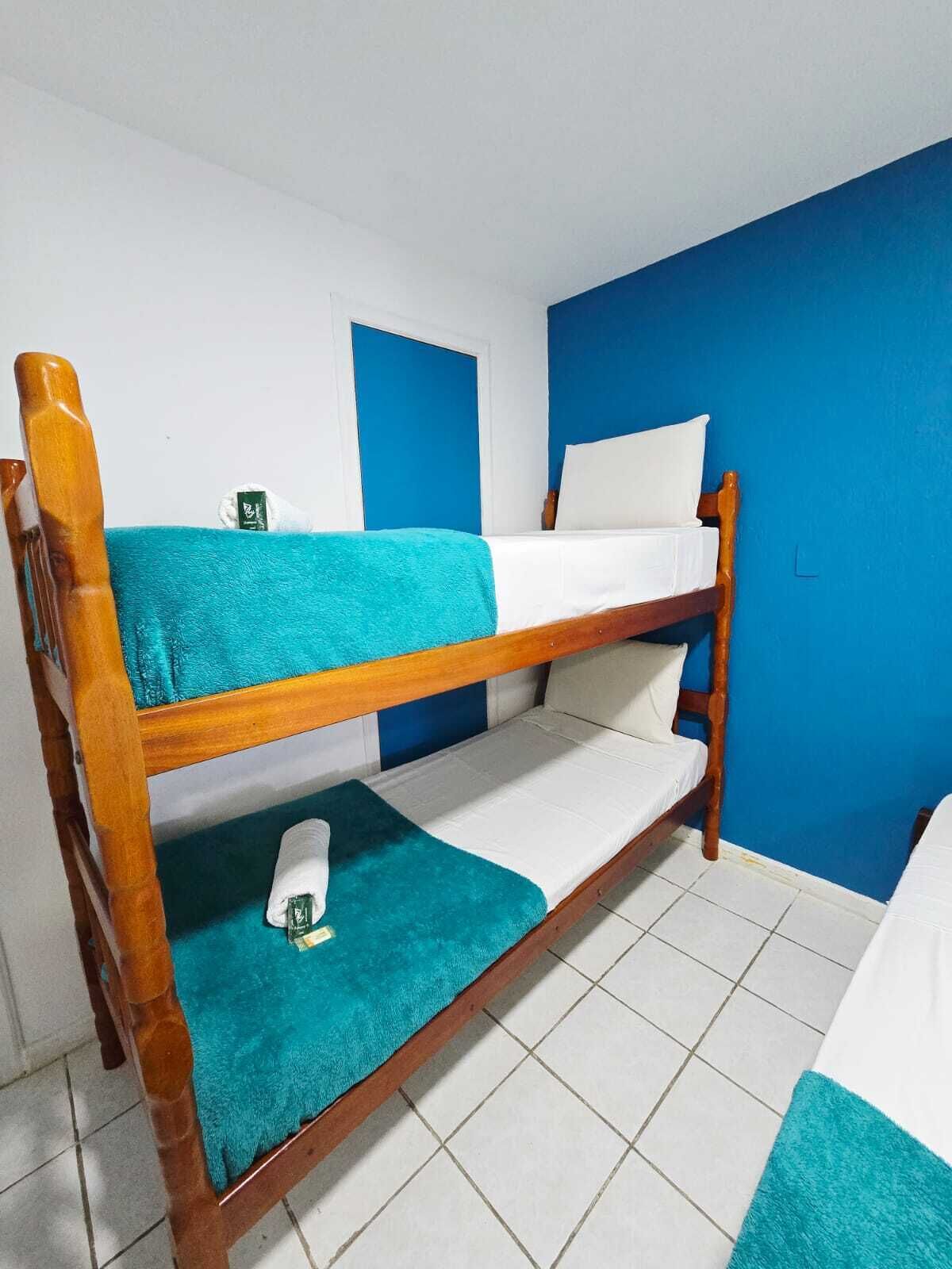 A bunk bed with a blue wall and white floor tiles.