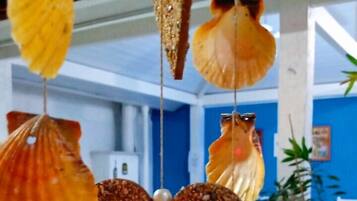 A room with a white table, chairs, and a hanging decoration of seashells and a heart-shaped ornament.