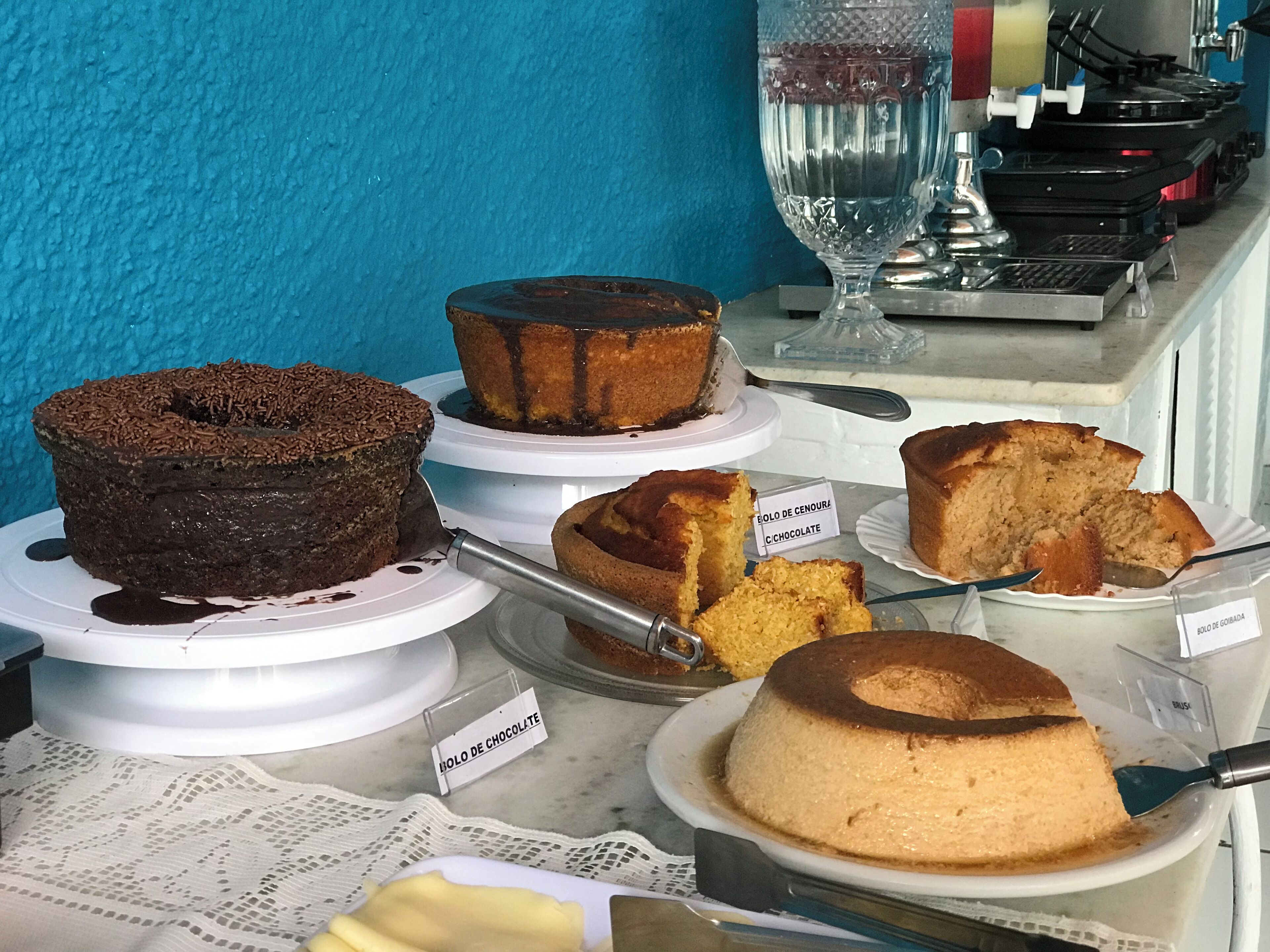 A display of various cakes on a counter with labels indicating their flavors.