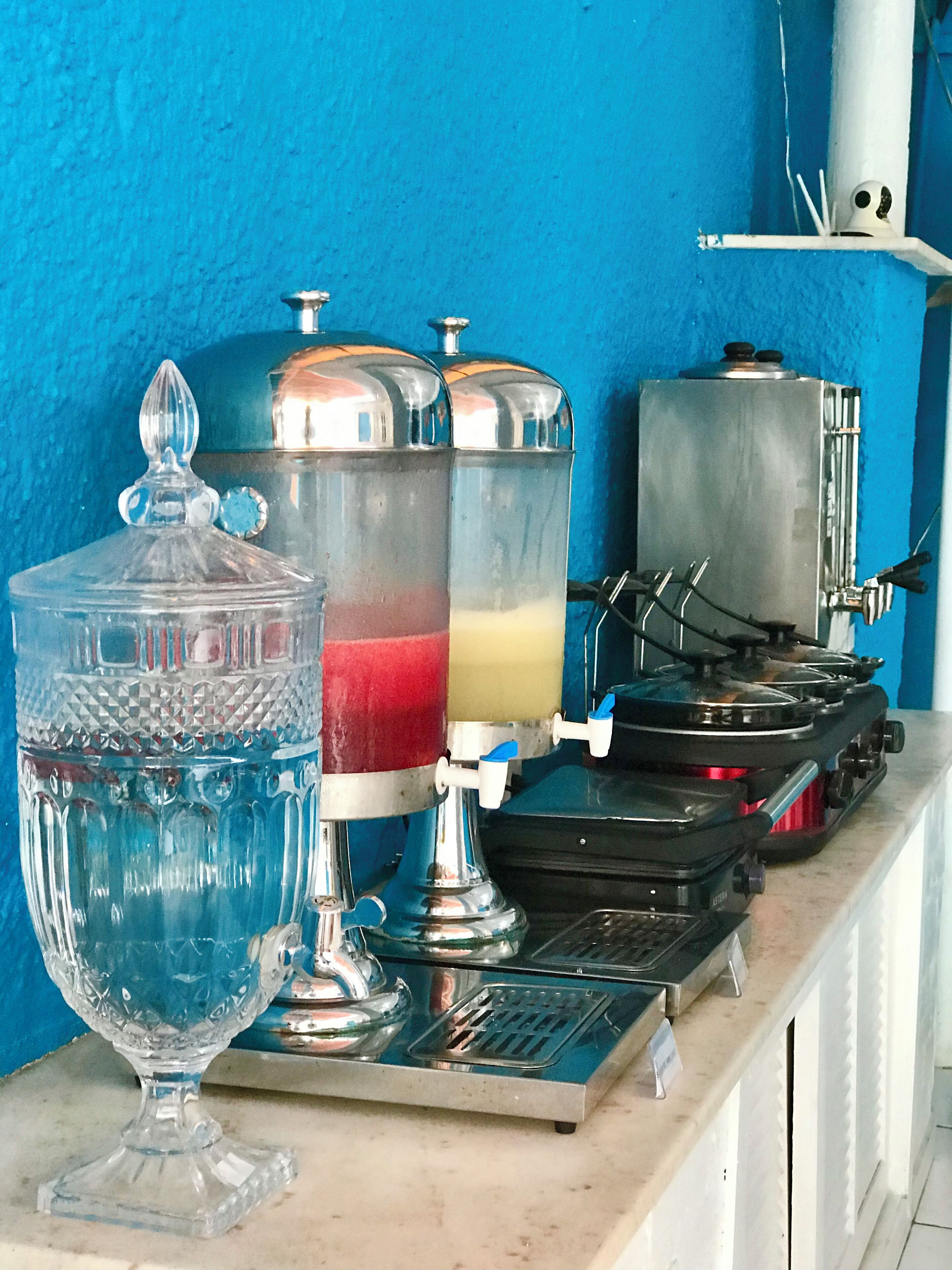 A beverage station with a large glass container, a metal dispenser, and a coffee machine.