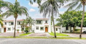 A white building with green trim, a central entrance, and a paved driveway.