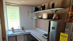 Ett kompakt kök med en diskho, en arbetsbänk och ett kylskåp i rostfritt stål.