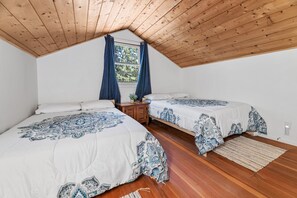 Un dormitorio con dos camas, techo de madera y una ventana con cortinas.