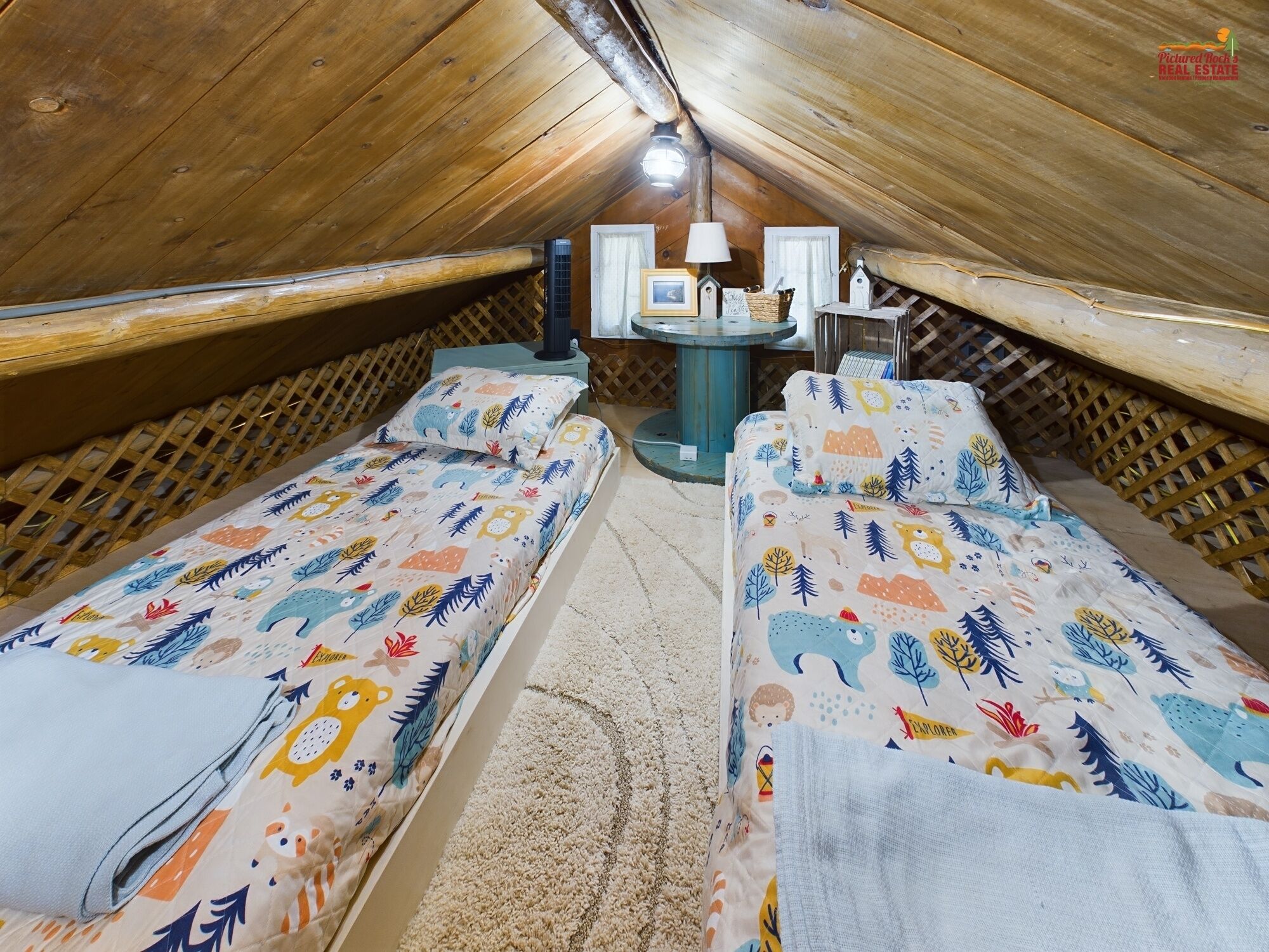 Ein gemütliches Schlafzimmer im Dachgeschoss mit zwei Einzelbetten, einem kleinen Tisch und einer Lampe.