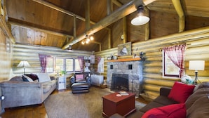 A cozy log cabin interior with a fireplace, wooden walls, and a comfortable seating area.