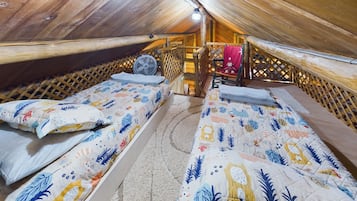 Une chambre confortable située dans les combles, avec deux lits, un ventilateur et une chaise.