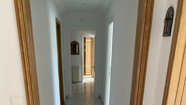 A hallway with marble flooring and wooden paneling. - THE GOOD ADRESS (Ariana)