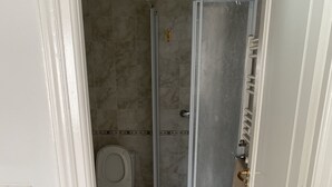 A bathroom with a shower enclosure, toilet, and a white door. - THE GOOD ADRESS (Ariana)