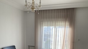 A bedroom with a bed, a nightstand, a radiator, and a window with curtains. - THE GOOD ADRESS (Ariana)