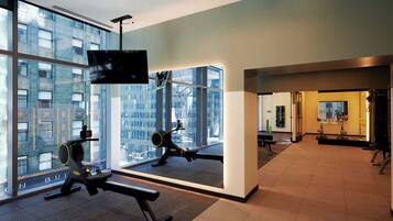 A modern gym with large windows, exercise equipment, and a television.