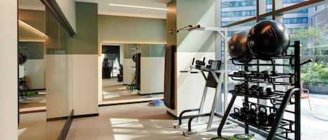 Un gimnasio moderno con equipo de levantamiento de pesas y amplias ventanas con vistas a la ciudad.