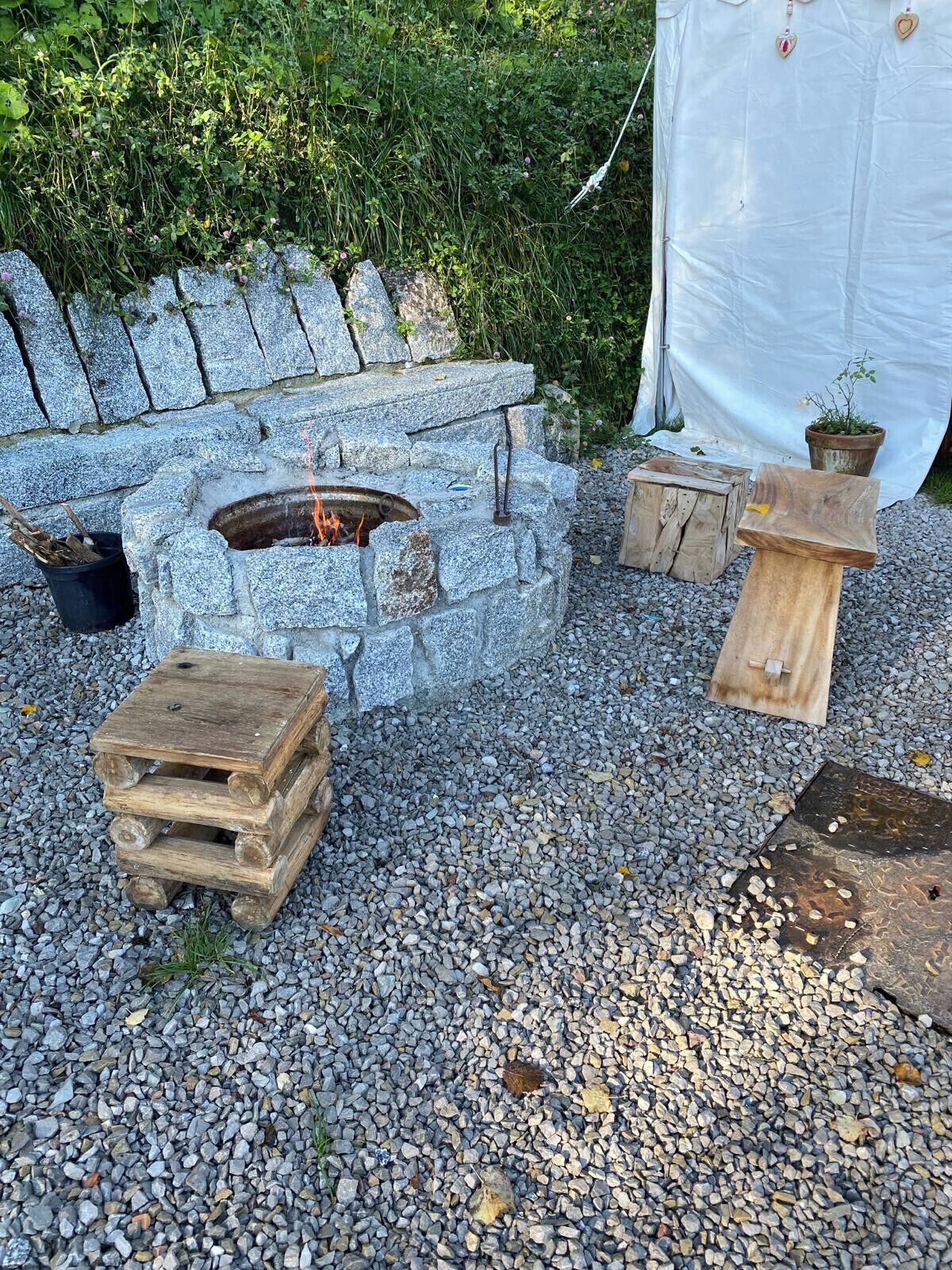 Ein Feuerkorb aus Stein mit einer hölzernen Bank und einem kleinen Tisch in der Nähe.