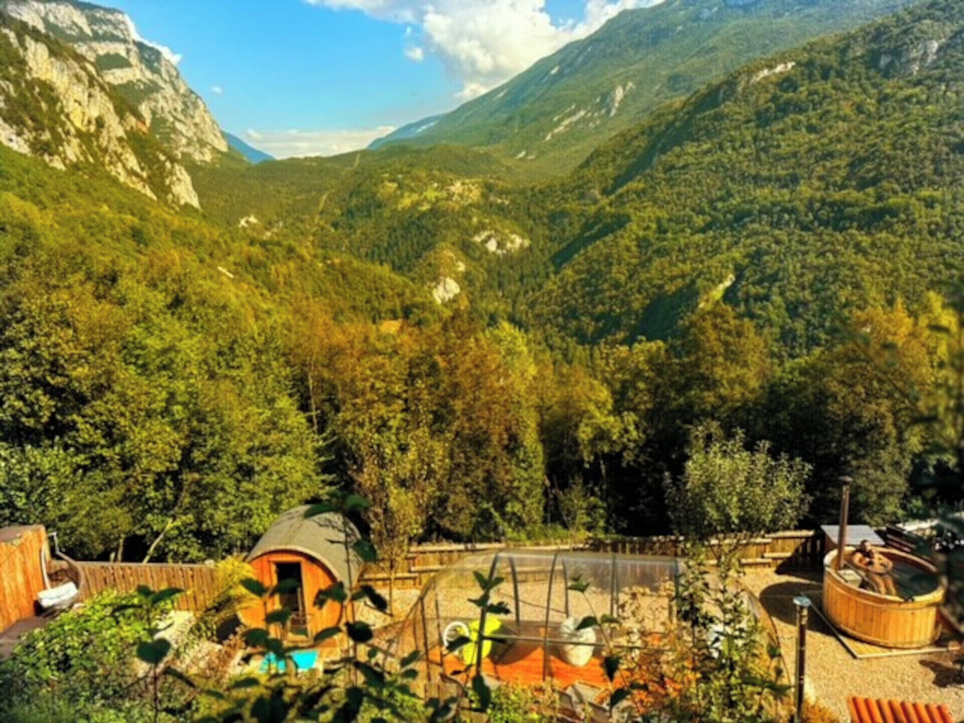 A mountain lodge with a wooden cabin, a hot tub, and a greenhouse.
