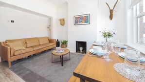 Ein modernes Wohnzimmer mit Sofa, Couchtisch, Kamin und Esszimmer, gedeckt für eine Mahlzeit.