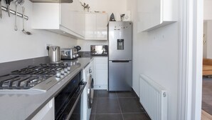 Eine kompakte Küche mit Gasherd, Backofen, Waschmaschine und einem Edelstahlkühlschrank.