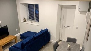 Un espacio habitable compacto con sofá, mesa de comedor y televisor.