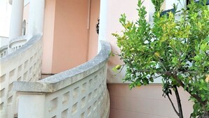 Um edifício com uma escadaria curva, uma pequena árvore e uma janela com design em arco.