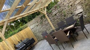 An outdoor patio with a stone wall, wooden pergola, and a grill station. - 6 Eyre Square Lane (Galway)