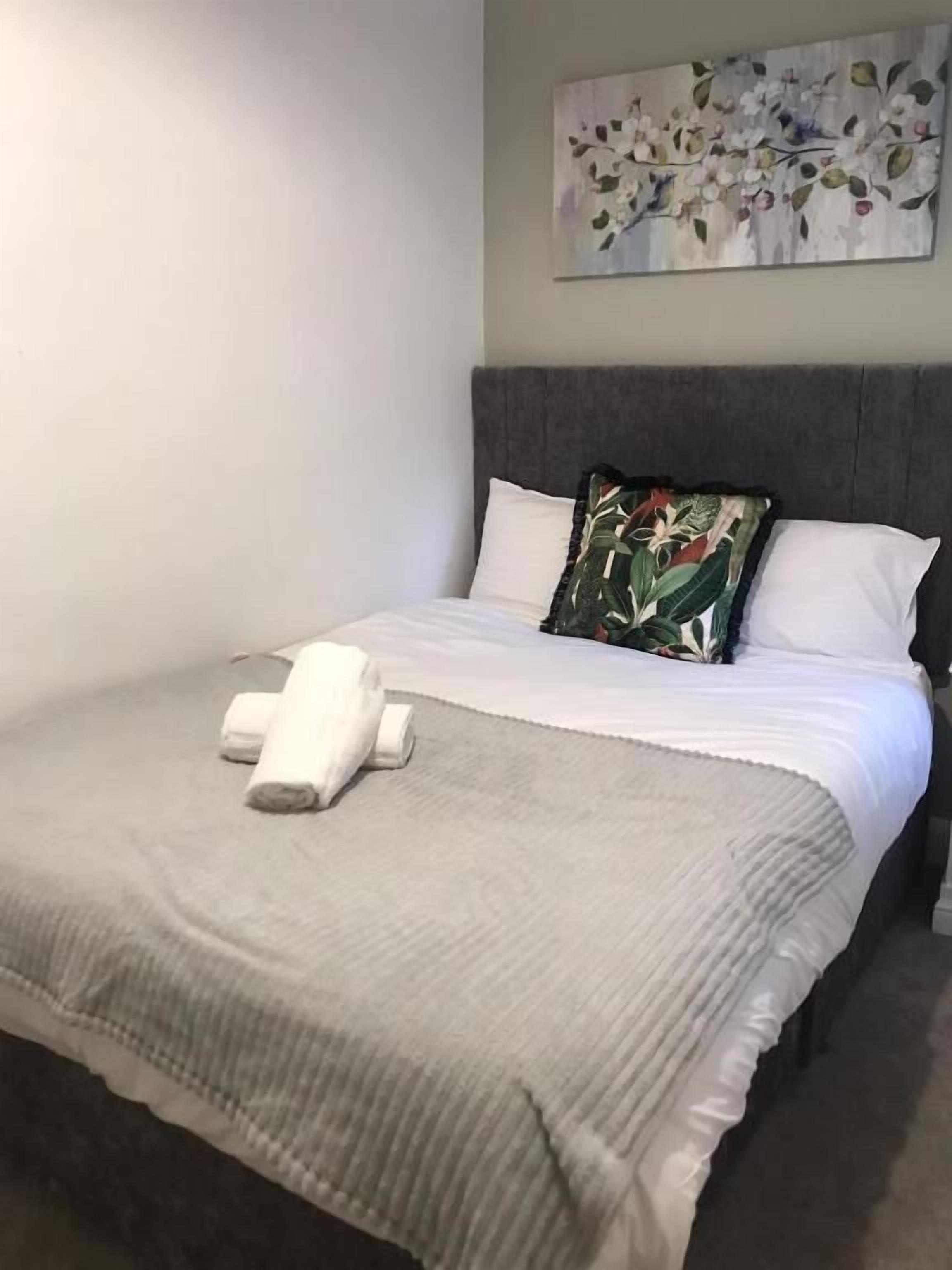 A neatly made bed with a grey blanket and a white pillow.