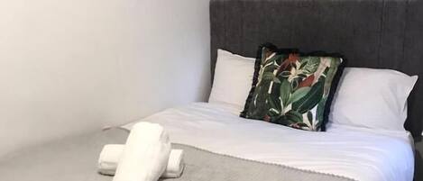 A neatly made bed with a grey blanket and a white pillow.