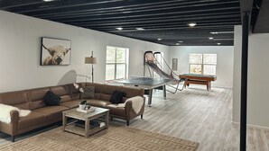 Ein geräumiges Wohnzimmer mit einer braunen Ledersofa, einem Couchtisch und einem Tischtennisplatten.