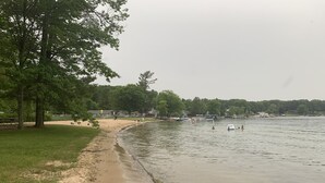 Ein Park am Seeufer mit Sandstrand, Bäumen und Booten.