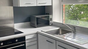 A modern kitchen with white cabinets, a built-in microwave, a stove, and a sink.