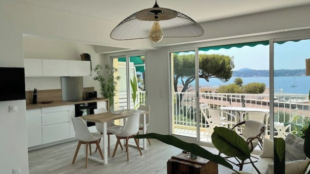 Una cocina moderna con armarios blancos, un comedor con sillas blancas y un amplio ventanal con vistas panorámicas.