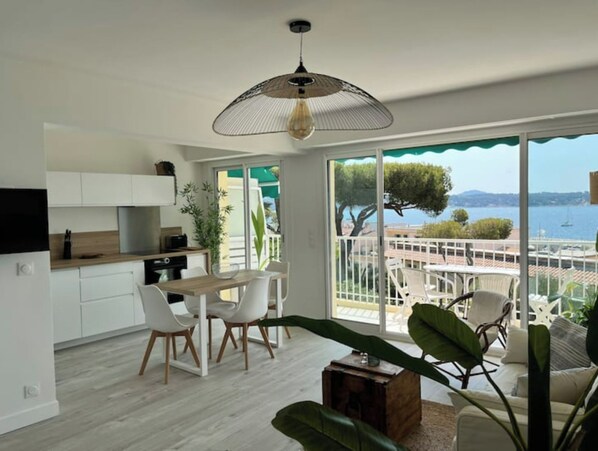 A modern kitchen with white cabinets, a dining area with white chairs, and a large window overlooking a scenic view.