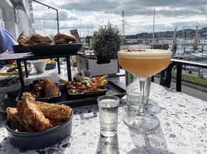 A table with a variety of food including fried chicken, a burger, and a salad, along with a cocktail and a glass of water. - Lovely Apartment 1 King 4 Single Beds (Torquay)