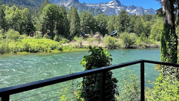 A river with a mountainous backdrop, surrounded by lush greenery and trees. - Small Timbers-riverfront log home, stunning view (Gold Bar)