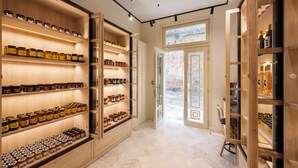 Un vaste couloir, agrémenté d’étagères en bois où sont exposés divers pots et bouteilles, mène à une grande porte vitrée.