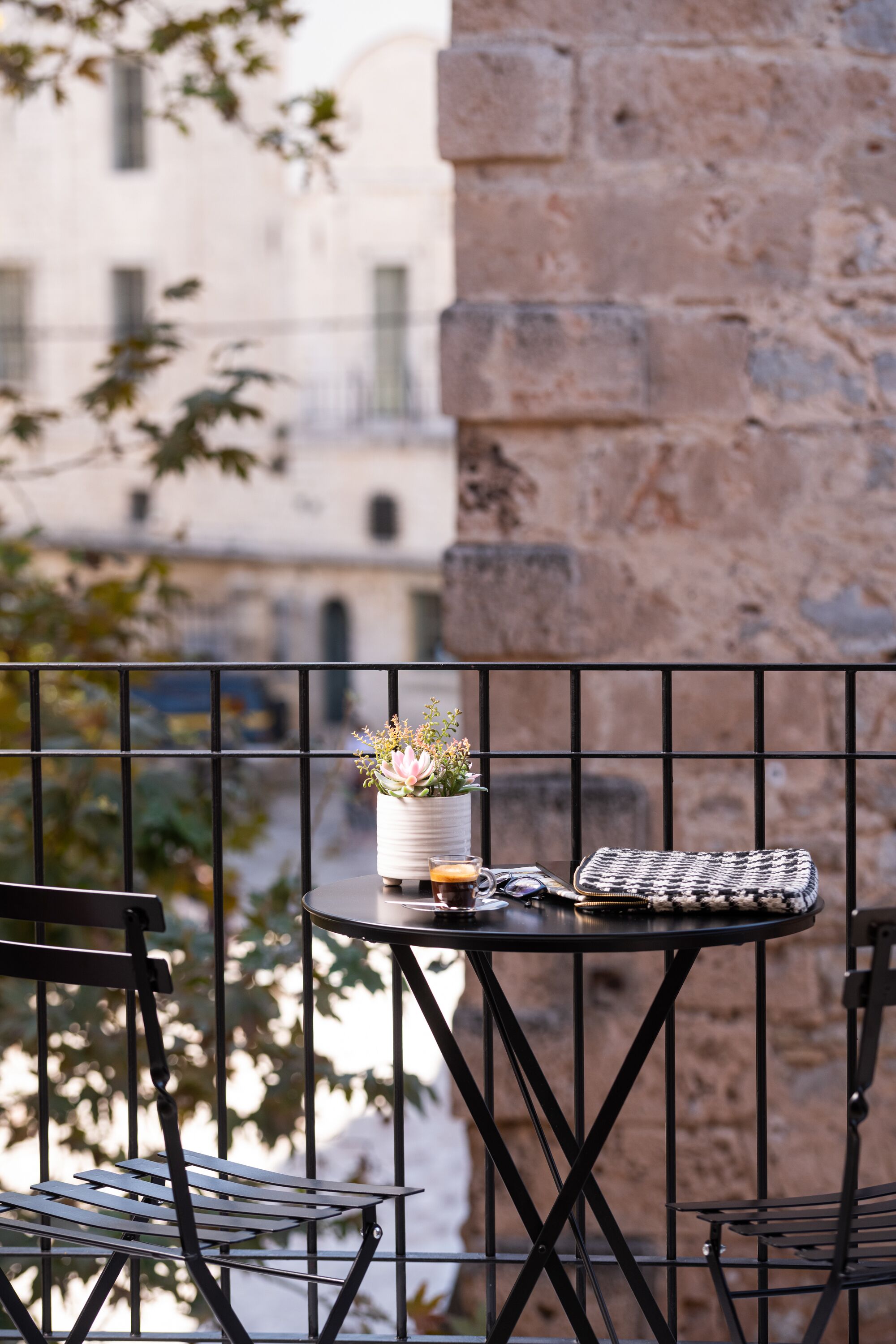 A balcony with a small round table, a chair, and a potted plant.