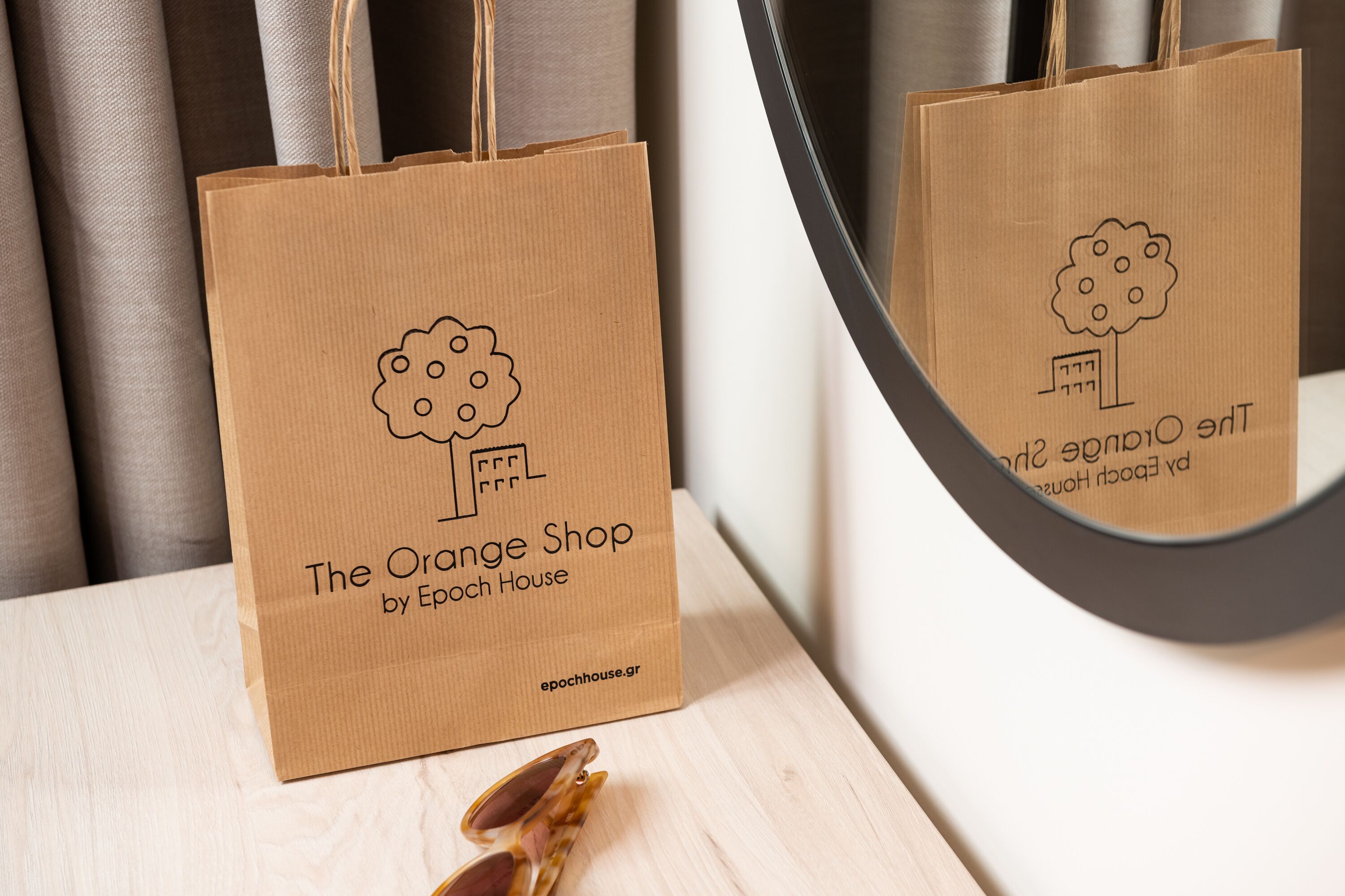 A brown paper bag with a tree and text on it, placed on a wooden surface.