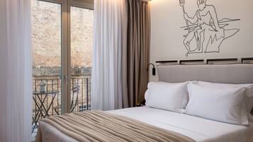 A bedroom with a large bed, a view of a balcony, and a wall mural.