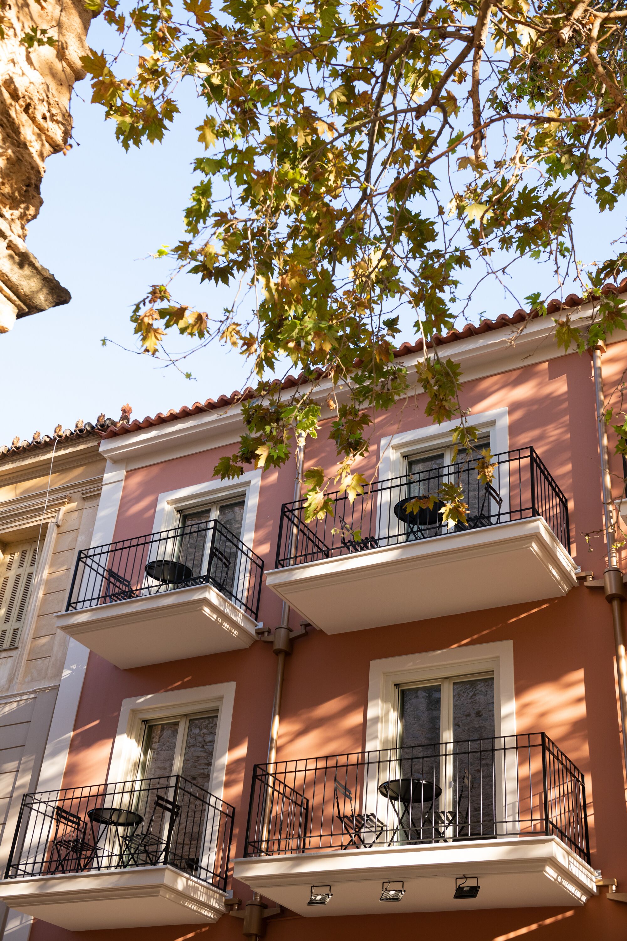 Un edificio con dos balcones, cada uno con una pequeña mesa y sillas.