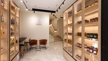 A modern interior with wooden shelving displaying jars, a staircase, and a small seating area.
