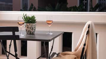 Une terrasse sur le toit avec une table, deux verres de vin, une plante en pot et une chaise avec une serviette.