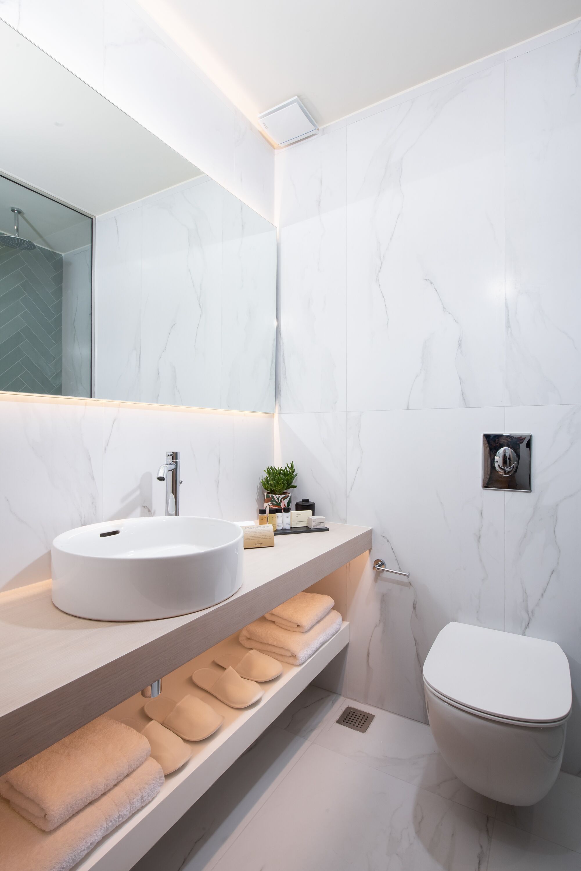 Une salle de bain moderne avec un grand lavabo blanc, un miroir et des toilettes.