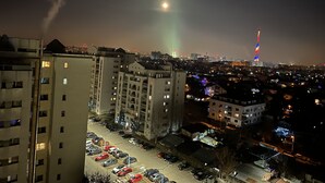 Un paisaje urbano nocturno con un edificio destacado que posee una torre alta con luces de colores.