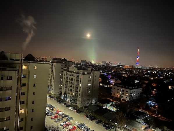 Un paisaje urbano nocturno con un edificio destacado que posee una torre alta con luces de colores.