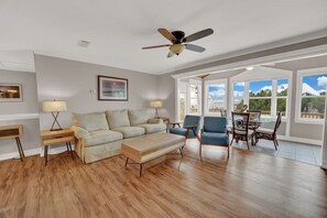 Relax in this serene living space with a comfortable sofa, wooden coffee table, and ceiling fan.