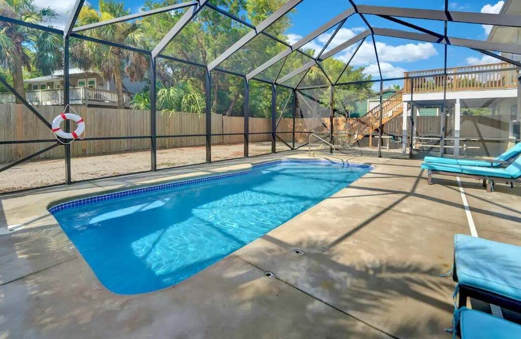 Ein überdachter Pool mit Rettungsboje, Liegestühlen und einer Holzterrasse.