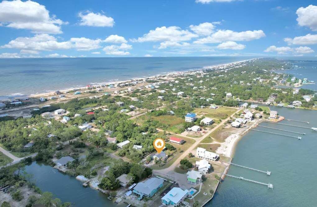 Vista aérea de una zona costera con un puerto deportivo, edificios residenciales y una playa.
