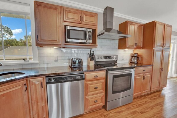 Enjoy cooking in this kitchen with a large window offering a view of the outdoors, featuring a dishwasher, oven, microwave, and coffee maker.
