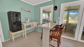 A compact kitchen with a refrigerator, a sink, and a bar area with a chair.