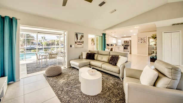 A spacious living room with a large sectional sofa, a coffee table, and a view of a pool through a sliding glass door.