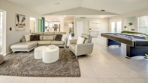 A spacious living room with a pool table, a sectional sofa, and a coffee table.