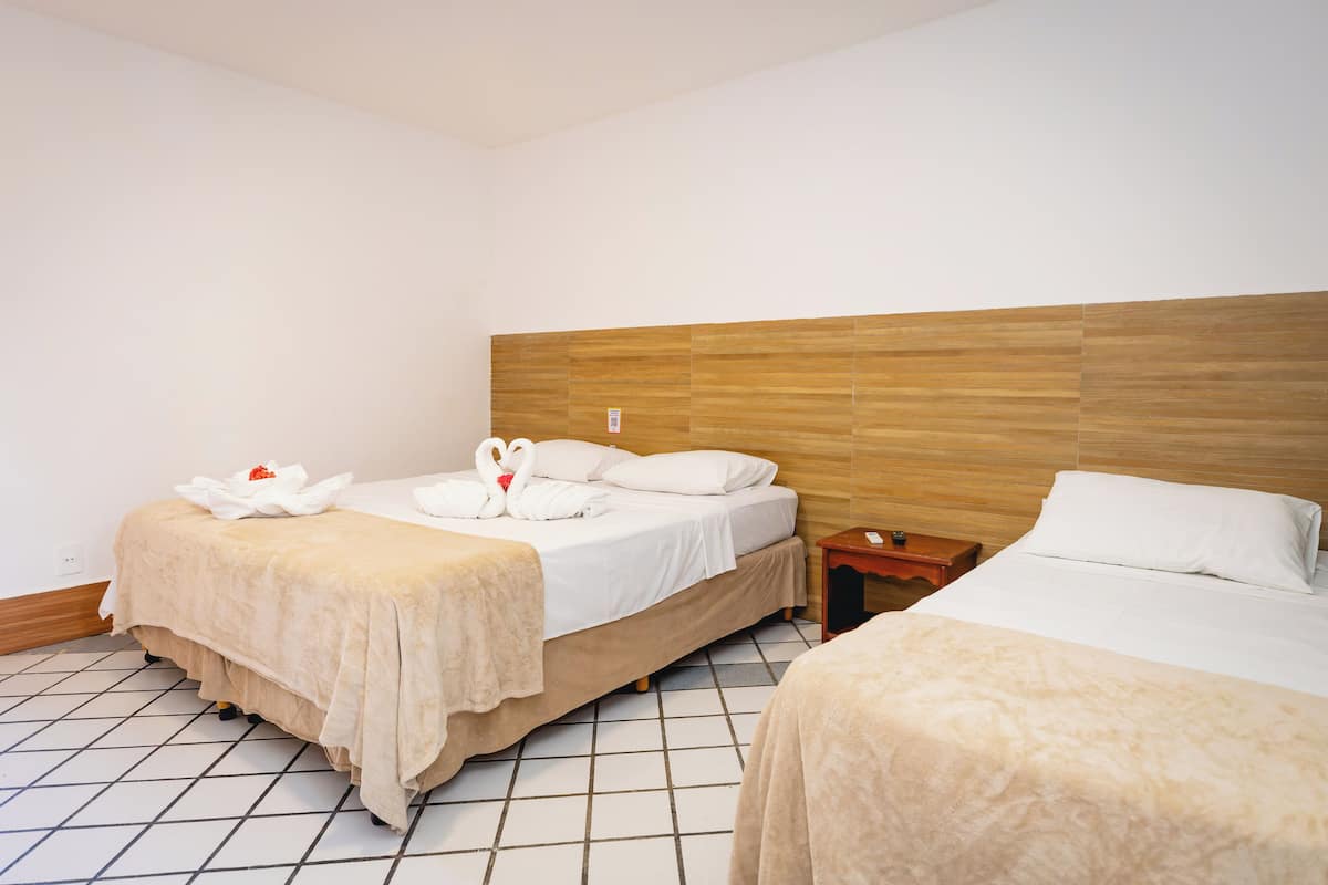 A hotel room with two beds, a wooden headboard, and a tiled floor.